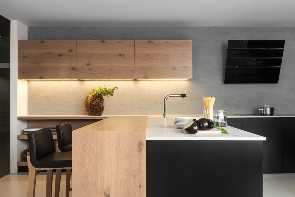 Immagine di una cucina moderna con ante lisce, ante nere, paraspruzzi grigio, elettrodomestici in acciaio inossidabile e penisola