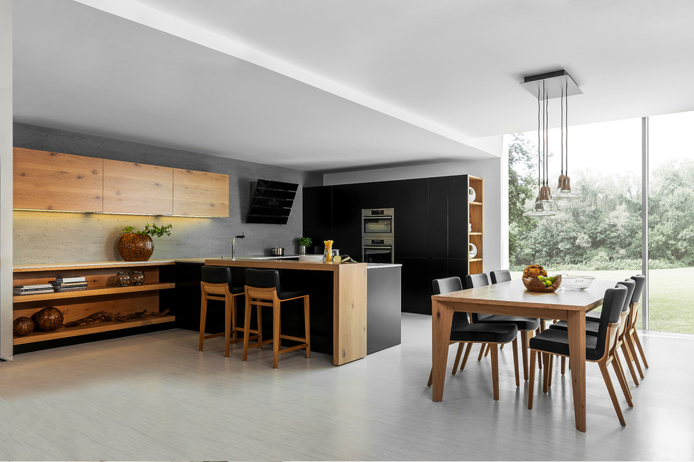 Imagen de cocina moderna grande con armarios con paneles lisos, electrodomésticos de acero inoxidable, península, puertas de armario negras y salpicadero verde