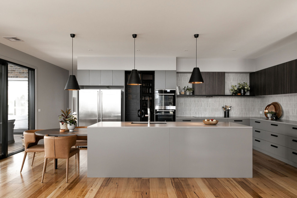 Inspiration for a large contemporary l-shaped brown floor kitchen remodel in Melbourne with an undermount sink, flat-panel cabinets, gray cabinets, gray backsplash, an island and gray countertops