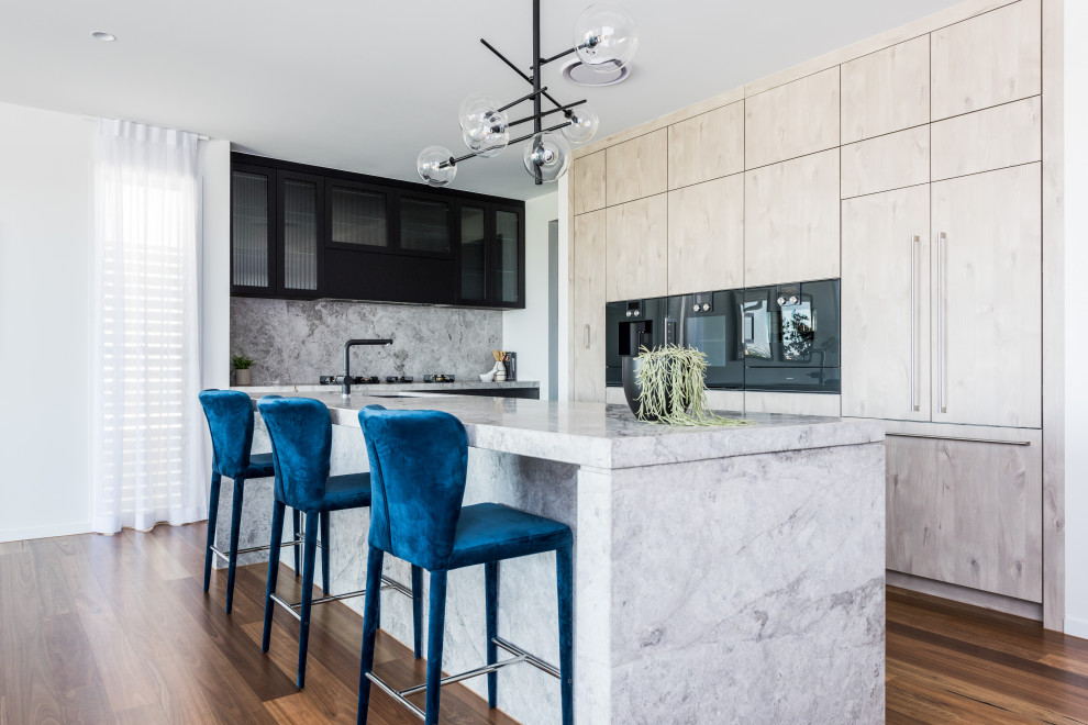 This is an example of an expansive contemporary kitchen in Brisbane with a submerged sink, flat-panel cabinets, limestone worktops, limestone splashback, black appliances and an island.