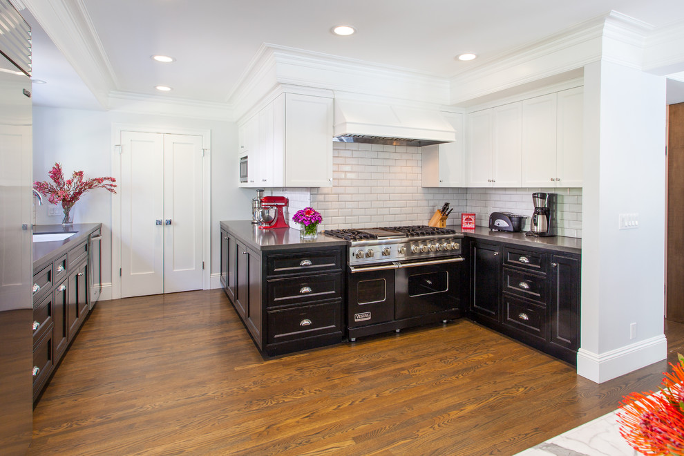 Inspiration for a classic kitchen in Los Angeles with recessed-panel cabinets, black cabinets, white splashback, metro tiled splashback, black appliances and medium hardwood flooring.