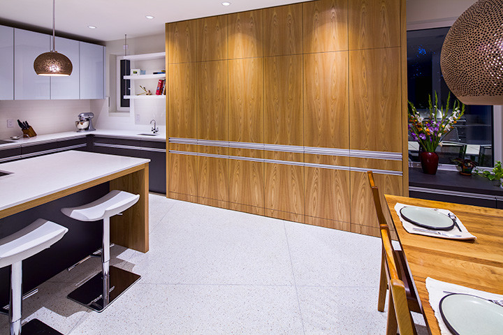 Photo of a medium sized contemporary u-shaped kitchen/diner in Calgary with flat-panel cabinets, grey cabinets, composite countertops, white splashback, metro tiled splashback, stainless steel appliances, an island and terrazzo flooring.