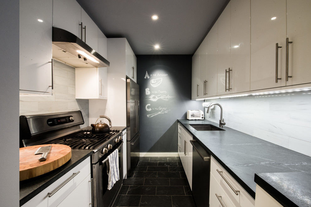 Medium sized retro galley kitchen/diner in New York with a submerged sink, flat-panel cabinets, white cabinets, concrete worktops, white splashback, stone tiled splashback, stainless steel appliances, marble flooring and no island.