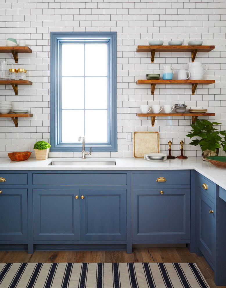 Design ideas for a large coastal galley open plan kitchen in Jacksonville with a double-bowl sink, flat-panel cabinets, white cabinets, marble worktops, blue splashback, porcelain splashback, stainless steel appliances, medium hardwood flooring, an island and brown floors.