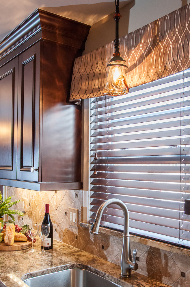 Exempel på ett klassiskt kök, med en undermonterad diskho, luckor med upphöjd panel, bruna skåp, granitbänkskiva, brunt stänkskydd, stänkskydd i stenkakel och rostfria vitvaror