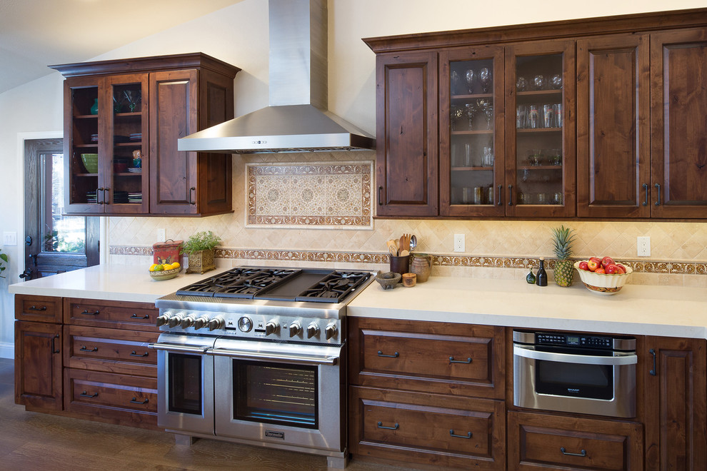 Exempel på ett stort lantligt kök, med en undermonterad diskho, luckor med upphöjd panel, skåp i mörkt trä, bänkskiva i kvarts, beige stänkskydd, stänkskydd i stenkakel, rostfria vitvaror, mellanmörkt trägolv och en köksö