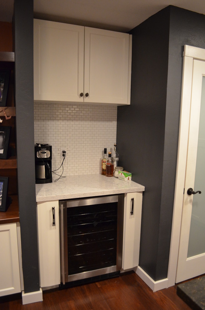 Example of a trendy dark wood floor kitchen design in Sacramento with recessed-panel cabinets, white cabinets, white backsplash and stainless steel appliances
