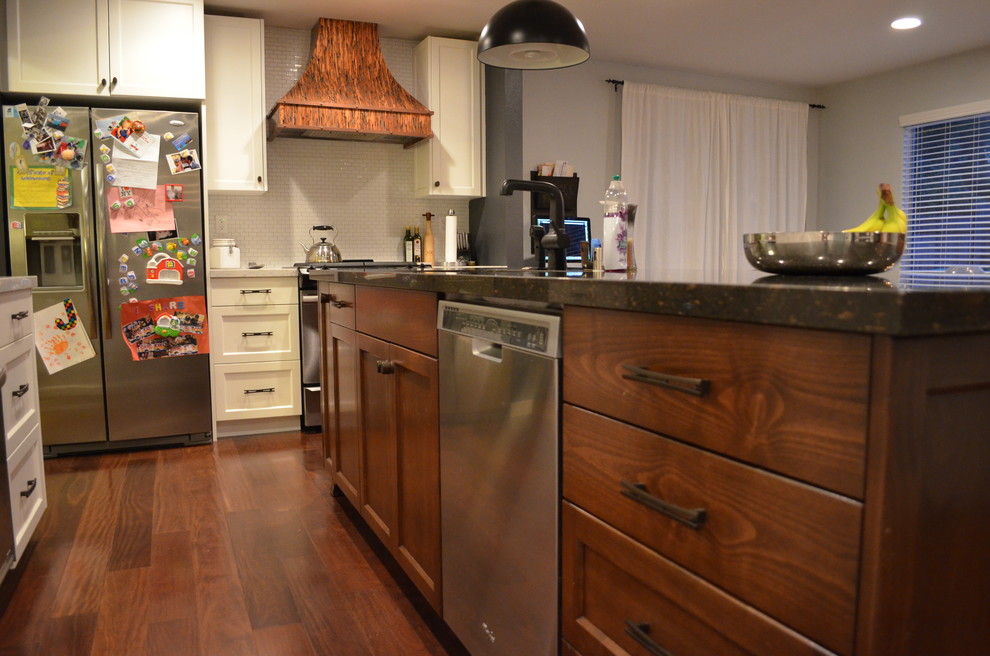 Example of a trendy dark wood floor kitchen design in Sacramento with an undermount sink, recessed-panel cabinets, dark wood cabinets, stainless steel appliances and an island