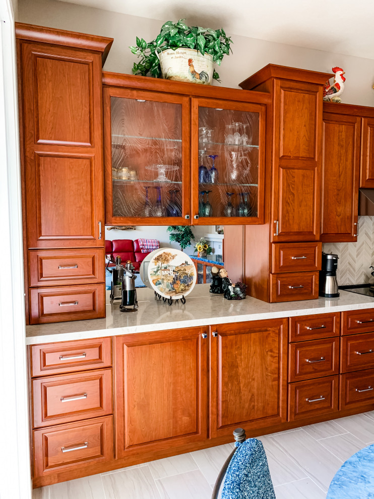 Inredning av ett klassiskt stort beige beige kök, med en enkel diskho, luckor med upphöjd panel, röda skåp, bänkskiva i kvarts, beige stänkskydd, stänkskydd i porslinskakel, rostfria vitvaror, klinkergolv i porslin, en köksö och beiget golv