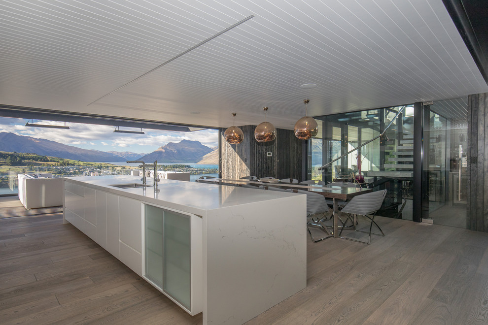 Cette photo montre une très grande cuisine ouverte parallèle moderne avec parquet foncé, îlot et un sol gris.