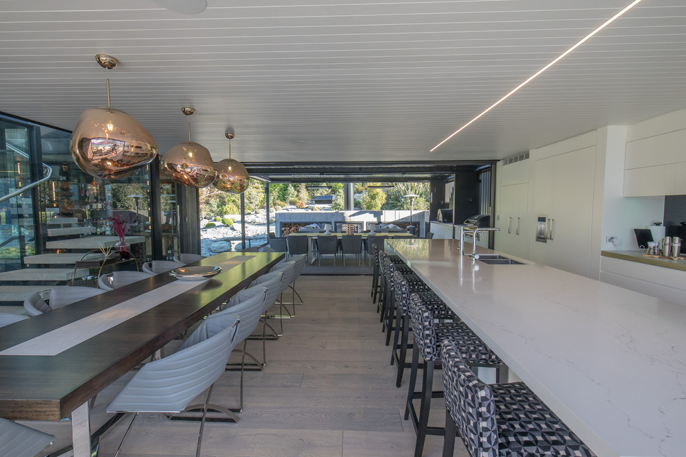 На фото: огромная параллельная кухня-гостиная в стиле модернизм с темным паркетным полом, островом и серым полом с