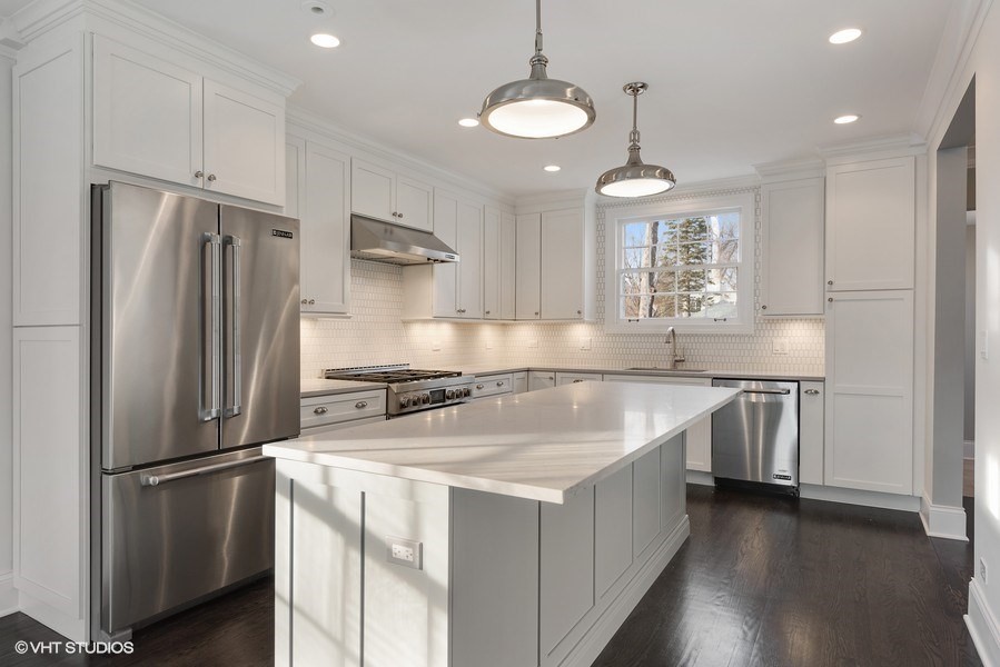 Inspiration for a transitional dark wood floor kitchen remodel in Chicago with an undermount sink, shaker cabinets, white cabinets, quartz countertops, white backsplash, porcelain backsplash and an island