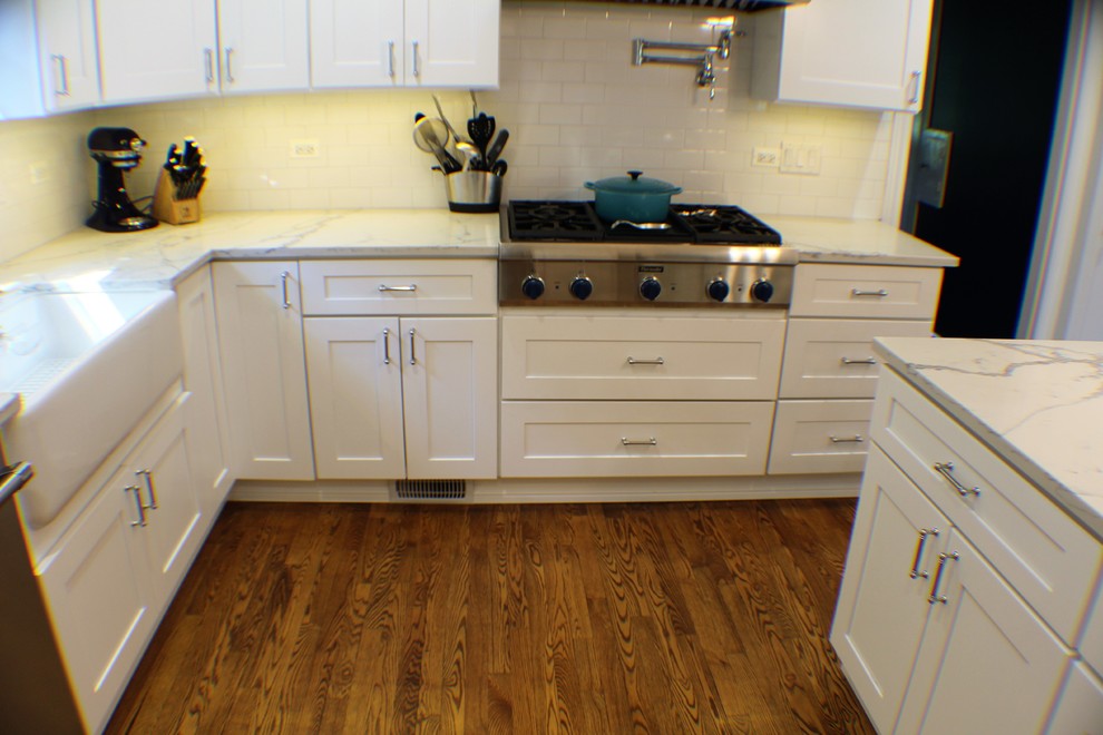 Bild på ett mellanstort funkis kök, med en rustik diskho, skåp i shakerstil, vita skåp, marmorbänkskiva, vitt stänkskydd, stänkskydd i tunnelbanekakel, rostfria vitvaror, mellanmörkt trägolv, en köksö och brunt golv