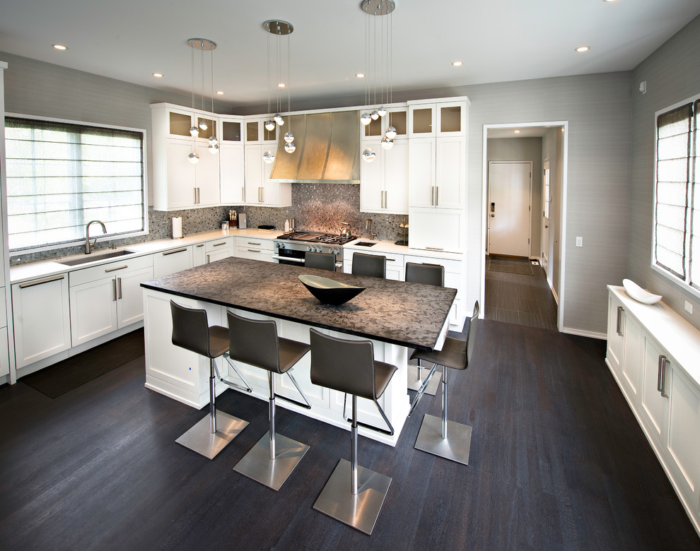 Inspiration for a mid-sized modern l-shaped dark wood floor and brown floor open concept kitchen remodel in Chicago with an undermount sink, shaker cabinets, white cabinets, solid surface countertops, gray backsplash, mosaic tile backsplash, paneled appliances and an island