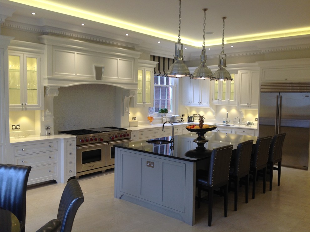 Design ideas for a large traditional l-shaped open plan kitchen in London with a double-bowl sink, shaker cabinets, white cabinets, quartz worktops, white splashback, porcelain splashback, stainless steel appliances, travertine flooring and an island.