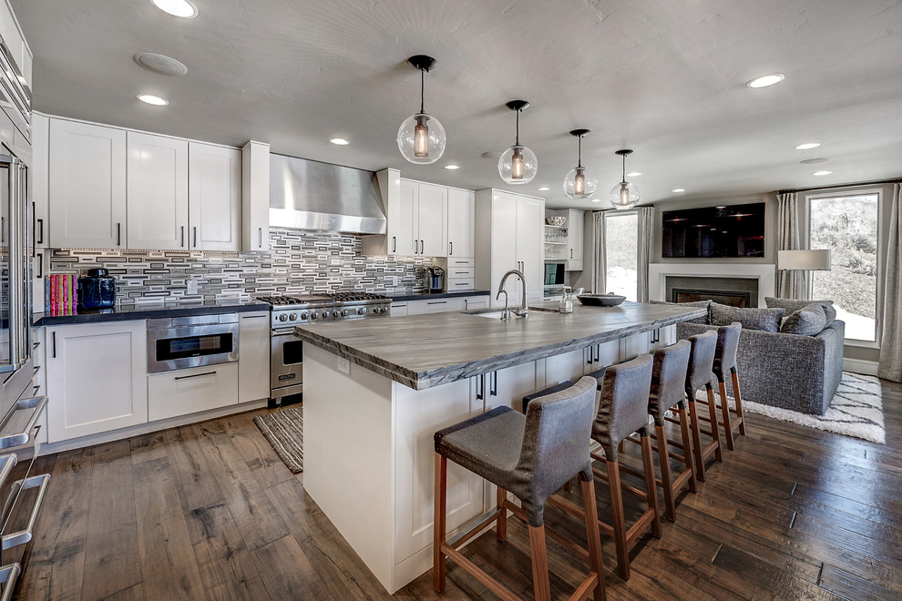 Transitional galley medium tone wood floor open concept kitchen photo in Denver with an undermount sink, shaker cabinets, white cabinets, stainless steel appliances and an island