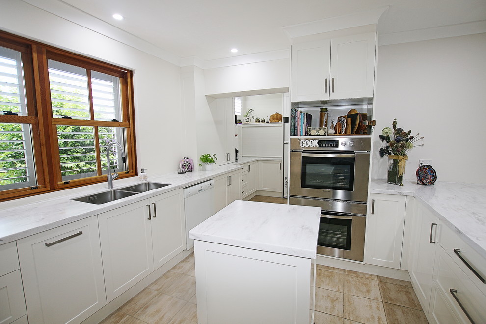 Example of a large classic u-shaped ceramic tile kitchen pantry design in Sydney with a double-bowl sink, shaker cabinets, white cabinets, solid surface countertops, brown backsplash, stone slab backsplash, stainless steel appliances and a peninsula
