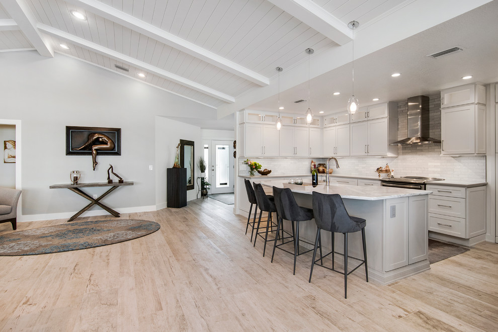 Large nautical u-shaped open plan kitchen in Orlando with a submerged sink, shaker cabinets, white cabinets, engineered stone countertops, white splashback, marble splashback, stainless steel appliances, porcelain flooring, an island and beige floors.