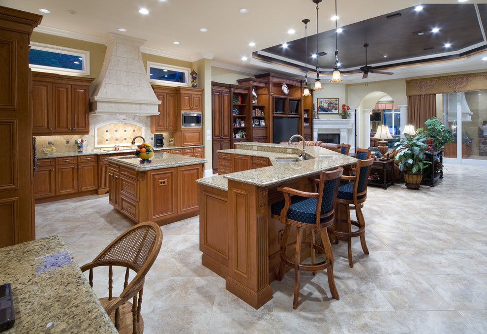 Inspiration for a mediterranean kitchen in Orlando with raised-panel cabinets, brown cabinets, granite worktops, stone tiled splashback, stainless steel appliances and ceramic flooring.