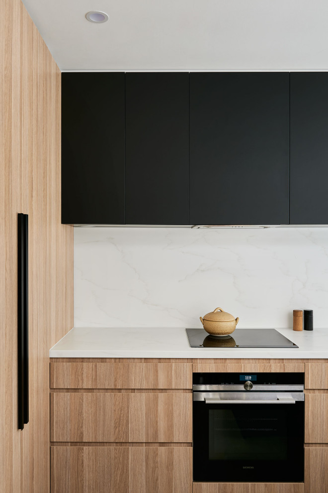 Inredning av ett modernt litet vit vitt kök, med en undermonterad diskho, skåp i ljust trä, bänkskiva i kvarts, vitt stänkskydd, rostfria vitvaror, betonggolv, en köksö och grått golv