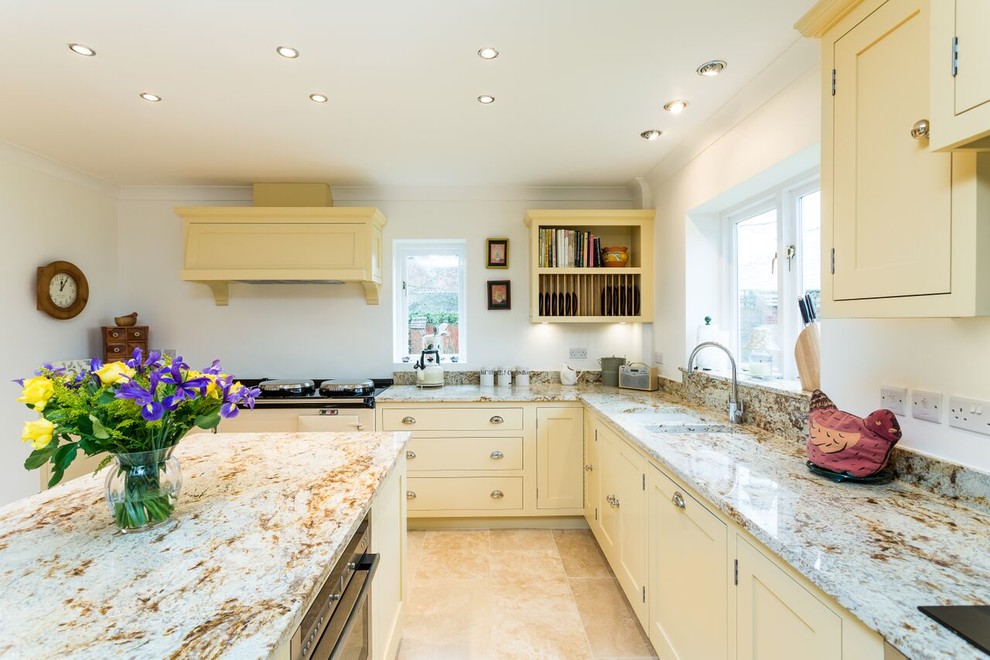 This is an example of a large classic l-shaped enclosed kitchen in Oxfordshire with a built-in sink, shaker cabinets, white cabinets, granite worktops, white splashback, stone slab splashback, stainless steel appliances, ceramic flooring and an island.