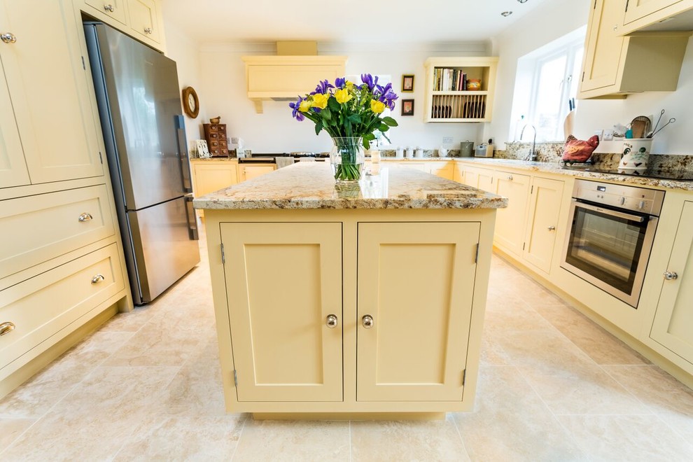 Large traditional l-shaped enclosed kitchen in Oxfordshire with a built-in sink, shaker cabinets, white cabinets, granite worktops, white splashback, stone slab splashback, stainless steel appliances, ceramic flooring and an island.