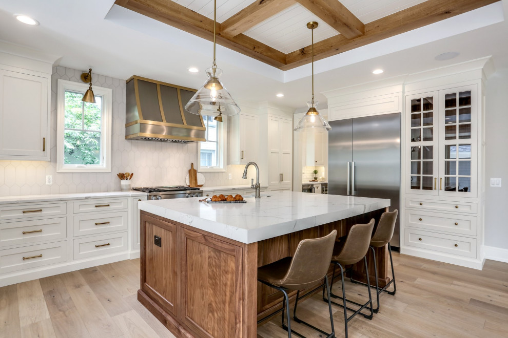 Large traditional kitchen in Detroit with a belfast sink, white splashback, stainless steel appliances, light hardwood flooring, an island and exposed beams.