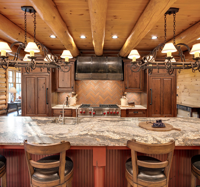 Photo of a large rustic l-shaped enclosed kitchen in Minneapolis with a belfast sink, raised-panel cabinets, medium wood cabinets, granite worktops, red splashback, terracotta splashback, stainless steel appliances and an island.