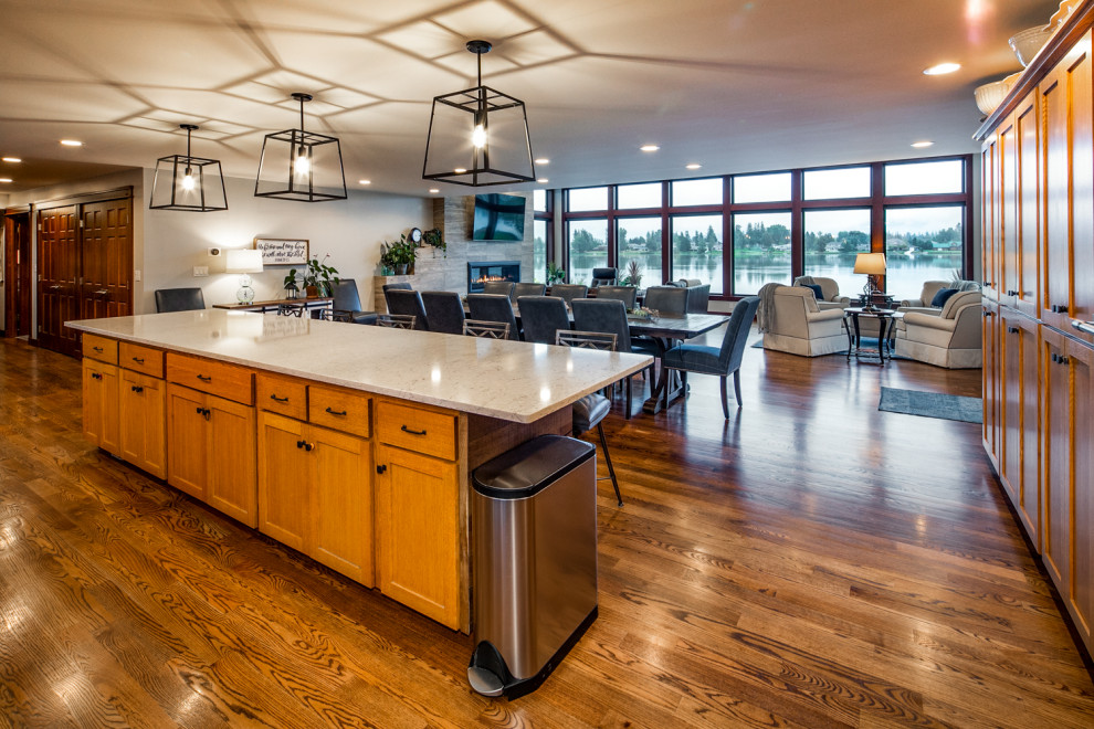 This is an example of a large contemporary u-shaped open plan kitchen in Seattle with a submerged sink, shaker cabinets, brown cabinets, quartz worktops, black splashback, porcelain splashback, stainless steel appliances, dark hardwood flooring, an island, brown floors and grey worktops.