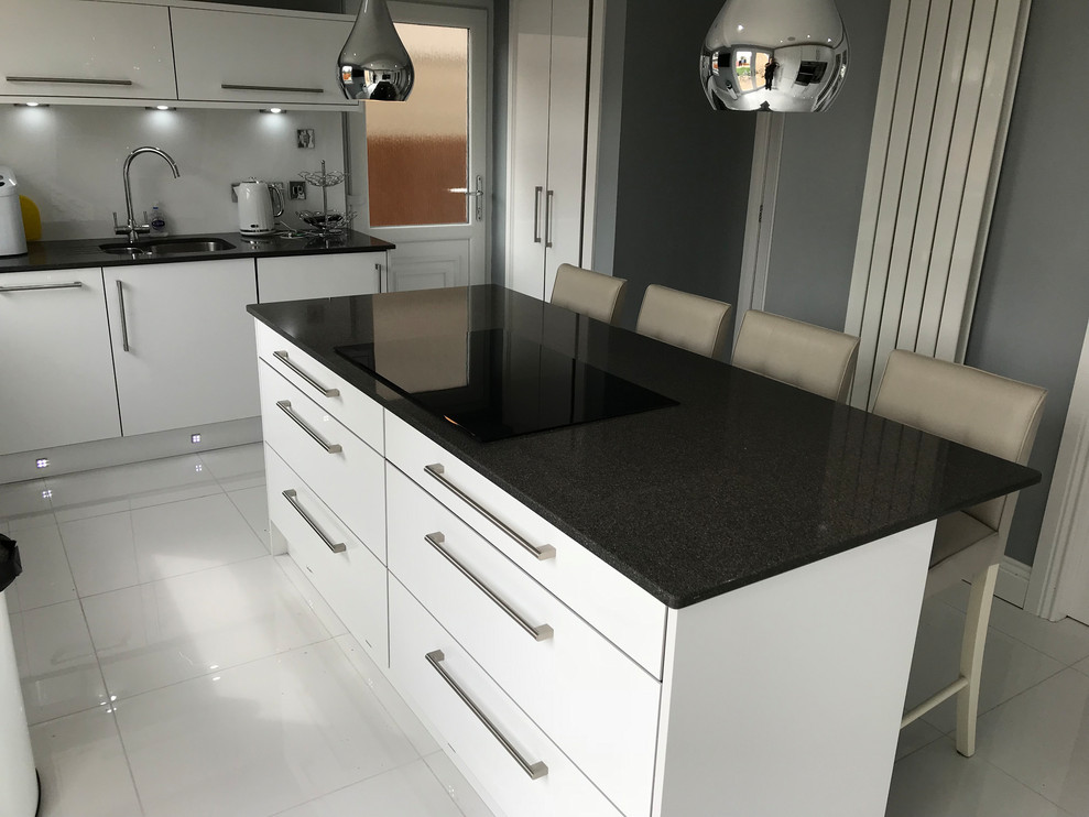 Immagine di una cucina minimal di medie dimensioni con ante lisce, ante bianche, top in quarzite, elettrodomestici in acciaio inossidabile, pavimento con piastrelle in ceramica, pavimento bianco e top nero