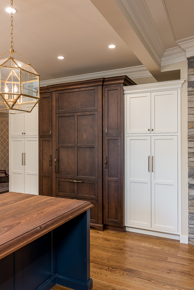 Diseño de cocina clásica con armarios estilo shaker, puertas de armario blancas, encimera de madera, electrodomésticos con paneles, suelo de madera clara y una isla