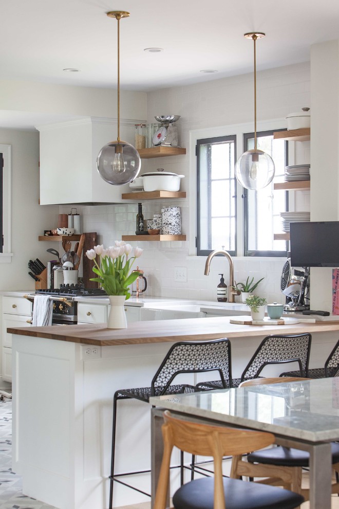 Eat-in kitchen - mid-sized modern l-shaped cement tile floor eat-in kitchen idea in Minneapolis with a farmhouse sink, recessed-panel cabinets, black cabinets, wood countertops, paneled appliances and a peninsula
