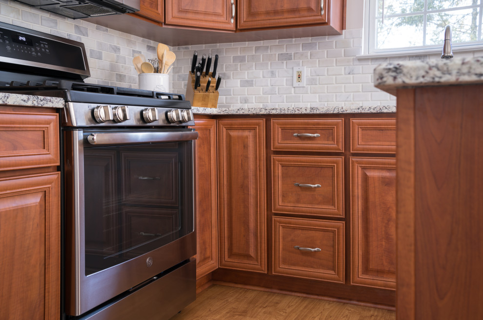 Inredning av ett klassiskt stort grå grått kök, med en enkel diskho, luckor med upphöjd panel, röda skåp, granitbänkskiva, grått stänkskydd, stänkskydd i marmor, rostfria vitvaror, mellanmörkt trägolv, en köksö och brunt golv