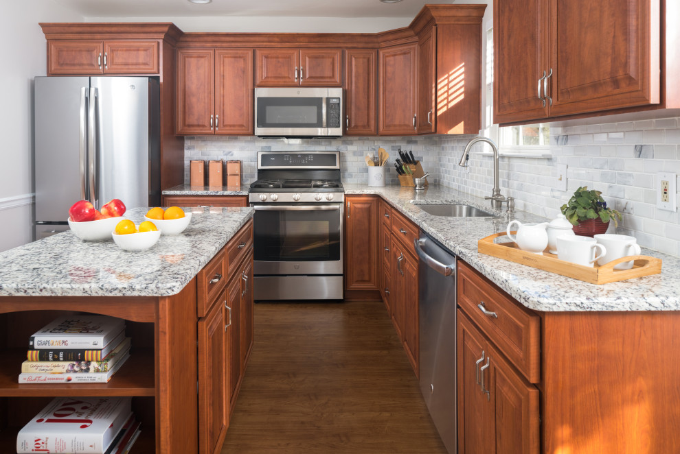 Klassisk inredning av ett stort grå grått kök, med en enkel diskho, luckor med upphöjd panel, röda skåp, granitbänkskiva, grått stänkskydd, stänkskydd i marmor, rostfria vitvaror, mellanmörkt trägolv, en köksö och brunt golv