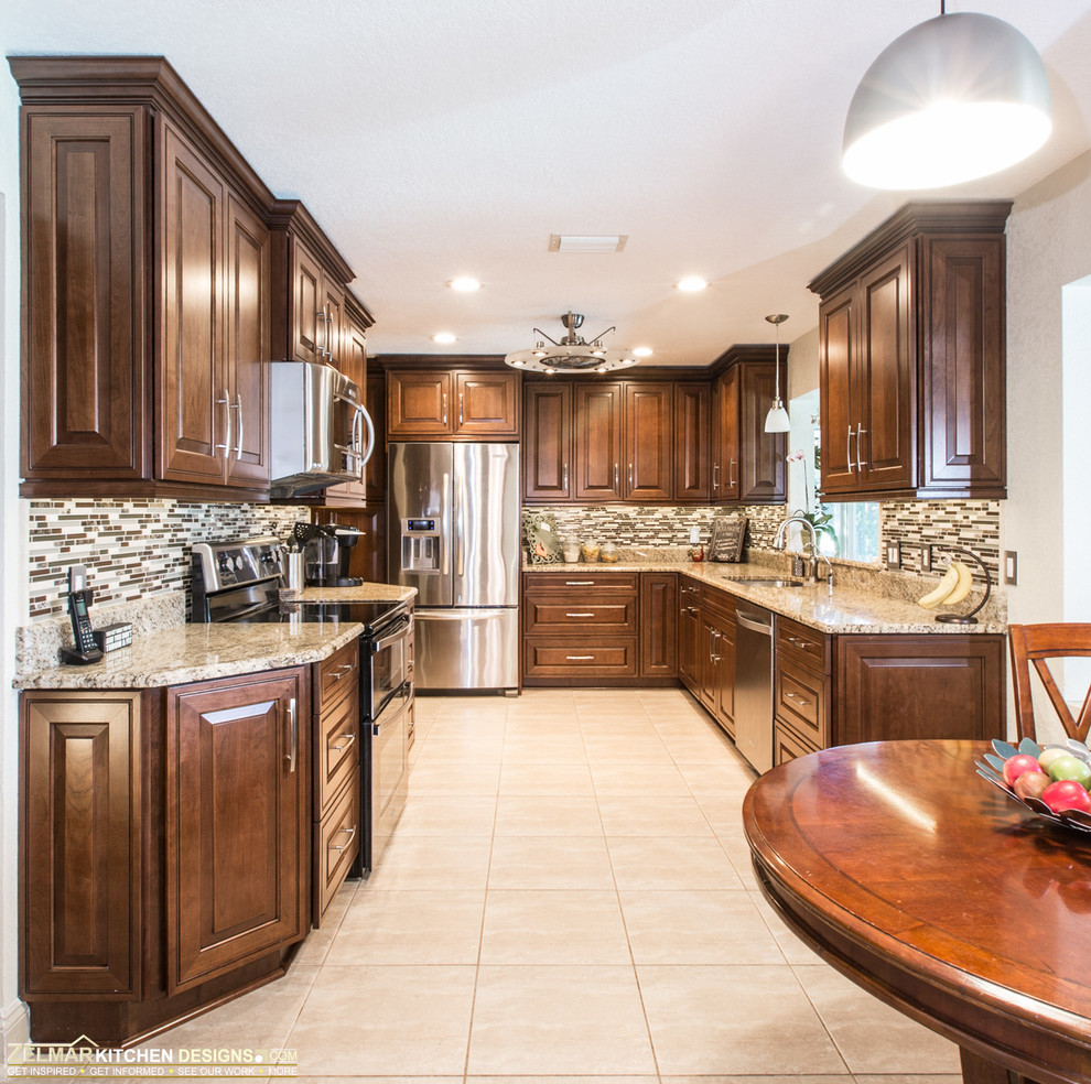 Example of a mid-sized classic u-shaped eat-in kitchen design in Orlando with an undermount sink, raised-panel cabinets, brown cabinets, granite countertops and beige backsplash