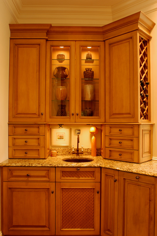 Inredning av ett klassiskt kök, med en undermonterad diskho, luckor med upphöjd panel, skåp i mellenmörkt trä, granitbänkskiva och integrerade vitvaror