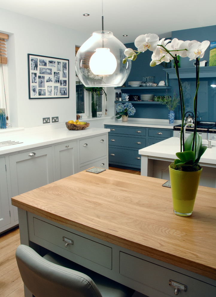 Inspiration for a kitchen in London with shaker cabinets, wood worktops, blue splashback, glass sheet splashback and multiple islands.