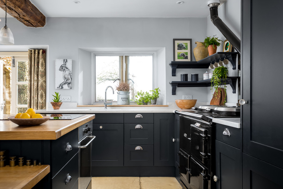 Offene, Mittelgroße Landhaus Küche in L-Form mit Schrankfronten mit vertiefter Füllung, schwarzen Schränken, Kücheninsel, integriertem Waschbecken, beigem Boden und weißer Arbeitsplatte in Gloucestershire