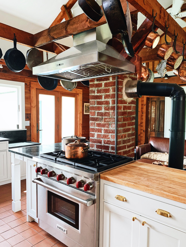 Idéer för ett mellanstort lantligt svart l-kök, med en rustik diskho, luckor med profilerade fronter, vita skåp, bänkskiva i täljsten, rostfria vitvaror, klinkergolv i keramik, en köksö och rött golv