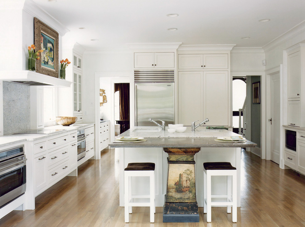 Geschlossene Klassische Küche in L-Form mit Küchengeräten aus Edelstahl, Unterbauwaschbecken, Schrankfronten im Shaker-Stil, weißen Schränken, Küchenrückwand in Grau, hellem Holzboden und Kücheninsel in Boston