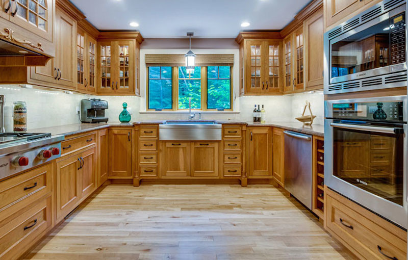 Immagine di una cucina ad U con ante in legno chiaro, top in granito, elettrodomestici in acciaio inossidabile e parquet chiaro