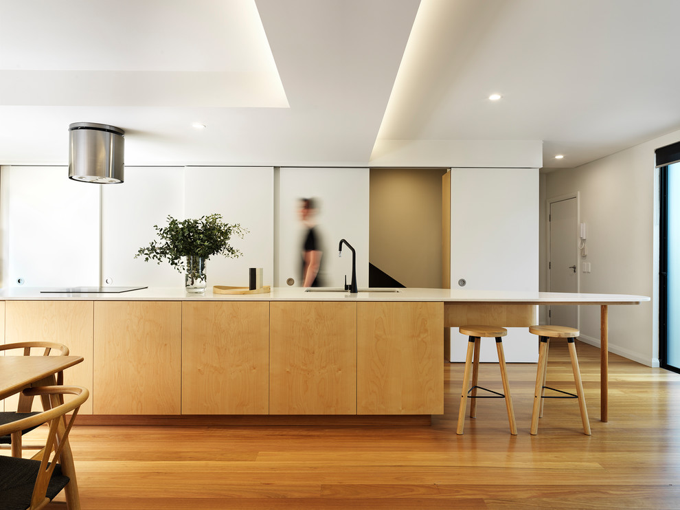 Moderne Küche mit Doppelwaschbecken, flächenbündigen Schrankfronten, hellen Holzschränken, braunem Holzboden, Kücheninsel, braunem Boden und weißer Arbeitsplatte in Sydney