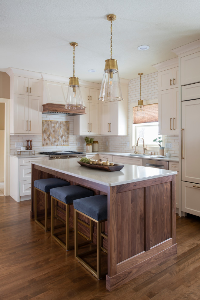Mid-sized transitional l-shaped medium tone wood floor and brown floor kitchen photo in Minneapolis with an undermount sink, shaker cabinets, quartz countertops, an island, white cabinets, white backsplash, subway tile backsplash, stainless steel appliances and white countertops