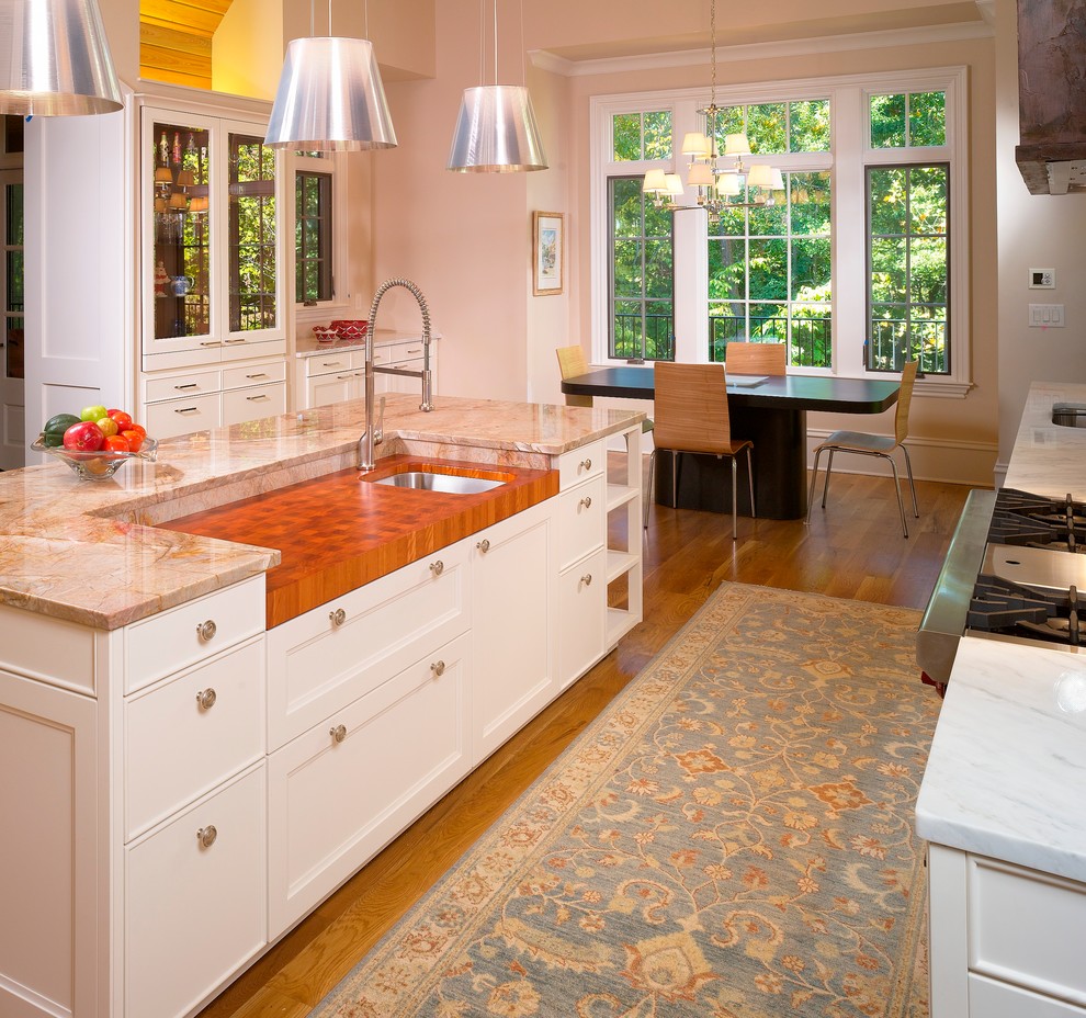 Пример оригинального дизайна: кухня в классическом стиле с обеденным столом, фасадами с утопленной филенкой, белыми фасадами и деревянной столешницей
