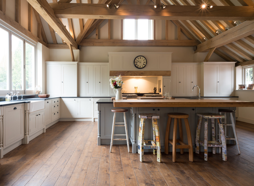 Landhausstil Wohnküche in L-Form mit Kücheninsel, Landhausspüle, Schrankfronten im Shaker-Stil, weißen Schränken und braunem Holzboden in Kent