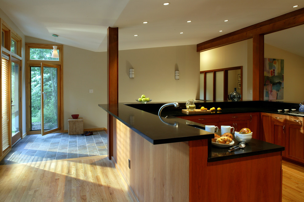 Inredning av ett modernt mellanstort kök, med en nedsänkt diskho, luckor med upphöjd panel, skåp i mellenmörkt trä, träbänkskiva, svart stänkskydd, stänkskydd i sten, rostfria vitvaror och ljust trägolv