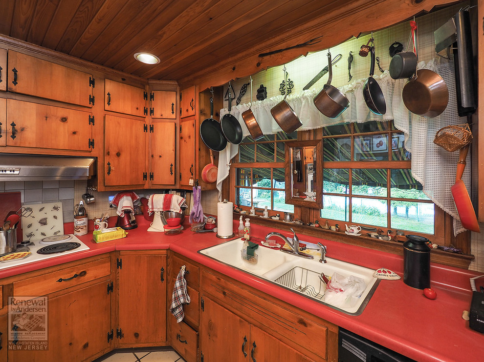 Foto på ett avskilt, mellanstort röd l-kök, med en nedsänkt diskho, skåp i mellenmörkt trä, laminatbänkskiva, beige stänkskydd, vita vitvaror, klinkergolv i keramik och beiget golv