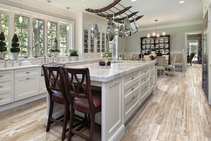 Exempel på ett lantligt kök och matrum, med luckor med upphöjd panel, vita skåp, marmorbänkskiva, vitt stänkskydd, rostfria vitvaror, klinkergolv i porslin och en köksö