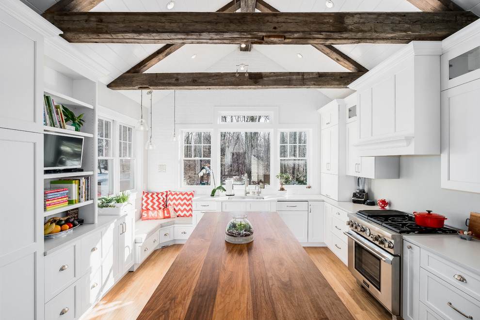 Inspiration pour une cuisine américaine rustique en L de taille moyenne avec un évier encastré, des portes de placard blanches, un plan de travail en quartz modifié, un électroménager en acier inoxydable, îlot, une crédence grise, parquet clair et un placard à porte shaker.