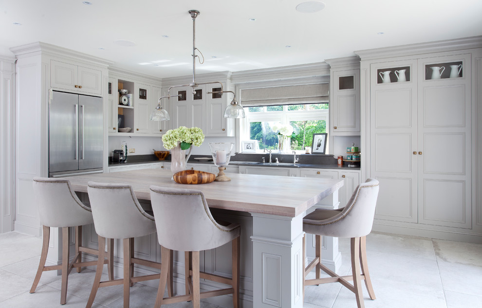 Inredning av ett klassiskt kök, med luckor med profilerade fronter, grå skåp, rostfria vitvaror, en köksö och grått golv
